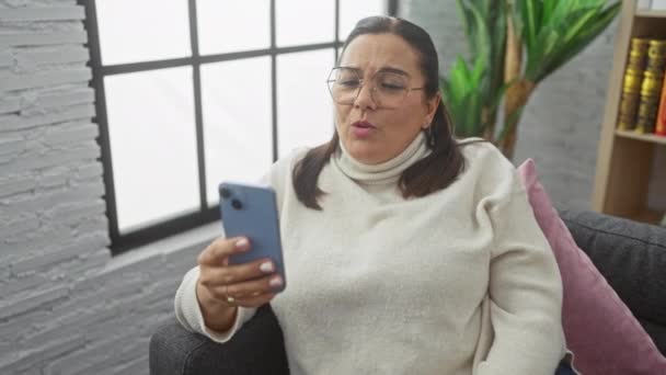 Hispanische Frau Telefoniert Smartphone Aus Gemütlichem Wohnzimmer Mit Modernem Dekor — Stockvideo