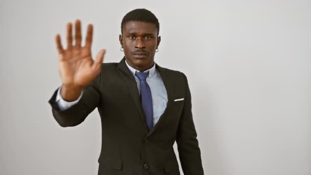スーツを着たアフリカ系アメリカ人のアサーティブな男性は 自信を持って手のひらで 彼の顔に深刻な警告の表現 白い背景に隔離された立場で — ストック動画