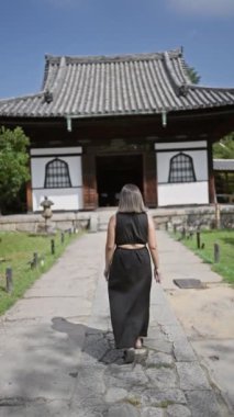 Neşeli, güzel İspanyol kadın, gururla poz veriyor gözlükleriyle, Kyoto 'nun dingin kodaiji tapınağında muhteşem bir gülümseme sergiliyor.