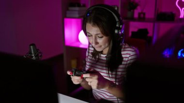 Geceleri renkli bir oyun odasında video oyunu oynayan odaklanmış bir kadın.