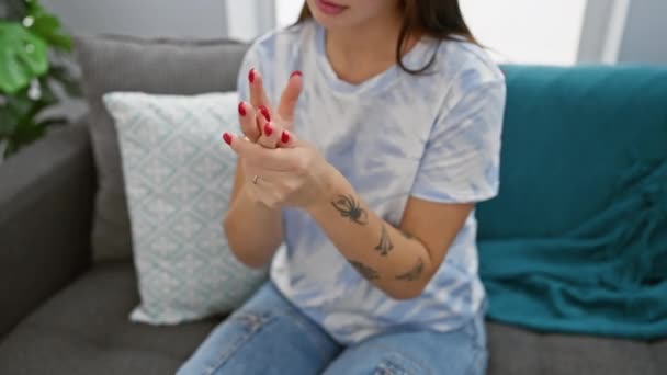 Młoda Kobieta Bada Ból Dłoni Pomieszczeniach Siedząc Kanapie Widocznym Tatuażem — Wideo stockowe
