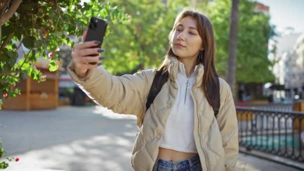 在一个阳光明媚的城市公园里 一个年轻的女人拿着智能手机自拍 — 图库视频影像