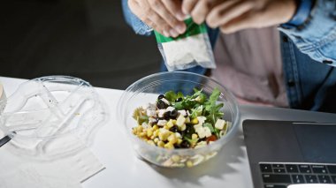 Bir insan iş yerinde taze bir salata mevsimi geçirir, bu da sağlık ve verimliliğe odaklandığını gösterir..