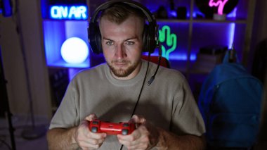 Sakallı, karanlık bir odada video oyunu oynayan, neon ışıklı ve kulaklık takan konsantre genç bir adam..