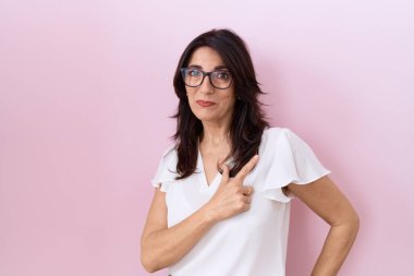 Orta yaşlı İspanyol kadın, günlük beyaz tişört ve gözlük takıyor. Neşeli gözlük takıyor. Yüzünde gülümseme var. 