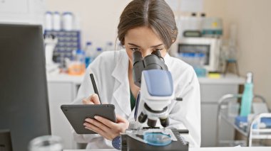 Laboratuvar ortamında mikroskop ve tablet kullanan kadın bilim adamı, araştırma, teknoloji, bilim, eğitim, sağlık hizmetleri, deney