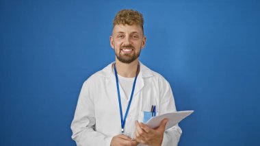 Sakallı, laboratuvar önlüğü ve halat takmış, elinde mavi arka planda bir pano tutan yakışıklı, beyaz bir adam..