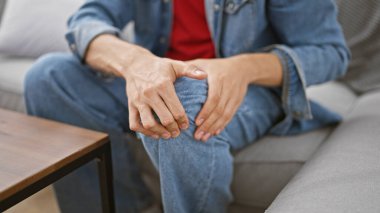 İspanyol asıllı bir adam kapalı bir koltukta otururken yaralı dizine dokunarak acı ya da yaralanma tasvir ediyor..