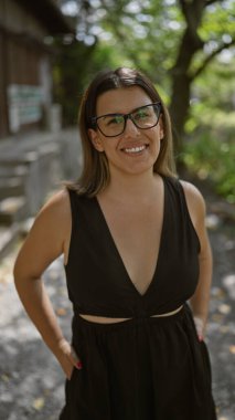 Kendine güvenen İspanyol kadın, güzel ve neşeli, gözlükleriyle neşeli poz veren, Kyoto 'nun geleneksel sokaklarında ayakta duran ve gülümseyen, doğal ve kaygısız Latin ifadesi yayan..