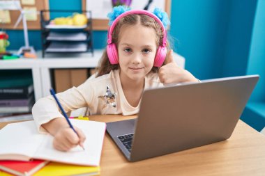 Sevimli beyaz kız öğrenci deftere yazı yazıyor ofiste müzik dinliyor.