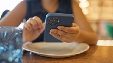 Genç ve güzel İspanyol kadın restoranda masanın üzerinde akıllı telefon kullanıyor.