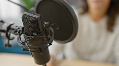 Modern bir stüdyoda profesyonel bir mikrofonla podcast 'e odaklanmış kadın kayıtları..