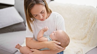 Evde, neşeli anne koltukta oturuyor, kendinden emin, sevgiyle gülüp geçen kızını uyutmaya çalışıyor, gülümseme dolu ilişkilerini geliştiriyor..
