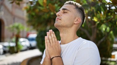 Genç bir İspanyol, açık hava ortamında huzur içinde meditasyon yapıyor..