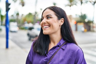 Young beautiful hispanic woman smiling confident looking to the side at street