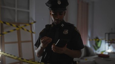 Afrika kökenli Amerikalı polis, loş ışıkta yanan bir suç mahallinde notlar alıyor..