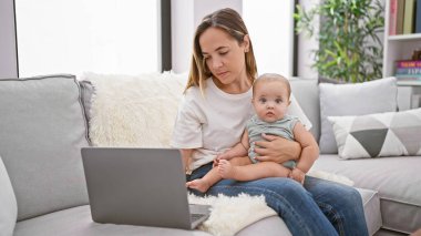 Rahat anne ve güzel kız evdeki kanepede oturuyor, dizüstü bilgisayarla online dünyayı keşfediyor, havalı, yavaş tempolu bir hayat sürüyor.