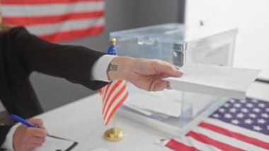 A woman casts her ballot at a united states electoral college with an american flag in view. clipart