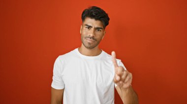 Sakallı yakışıklı, genç, İspanyol bir adam canlı kırmızı bir arka plana karşı el kol hareketi yapıyor.
