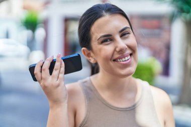 Genç ve güzel İspanyol kadın gülümsüyor. Caddedeki akıllı telefondan kendine güvenen bir sesli mesaj dinliyor.