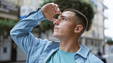 Sıradan giyinmiş yakışıklı bir İspanyol, bulanık bir sokak geçmişine tuhaf bir şekilde bakıyor..