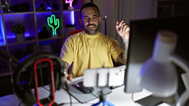 Geceleri karanlık bir oyun odasında sakallı, bilgisayar düzeneğine gülümseyen, ev eğlencesi çağrıştıran İspanyol bir adam..