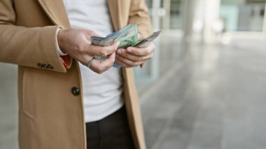 İspanyol adam şehir ortamında Malezya ringgitlerini sayıyor, şehir hayatı ve finans tasvir ediyor..