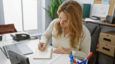 İspanyol kadın modern ofis ortamında notlar alıyor..