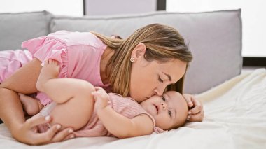 Neşeli anne kanepede uzanıyor, evde mutlu kızı öpüyor, güzel bir yaşam tarzı paylaşıyor.