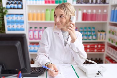 Eczanede çalışan genç, beyaz bir kadın telefonda konuşurken yüzünde gülümseme, doğal bir ifade vardı. Kendinden emin gülen. 