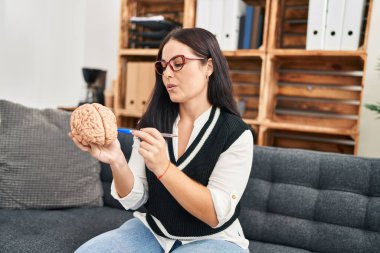 Psikoloji kliniğinde genç ve güzel bir İspanyol kadın psikolog parmak beynine işaret ediyor.