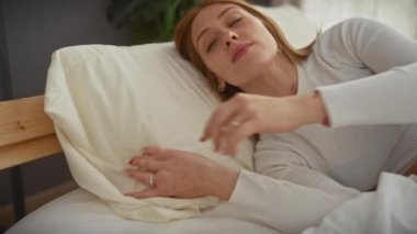 Huzurlu genç bir kadın rahat bir yatak odasında uyukluyor. Huzur ve huzuru somutlaştırıyor..