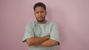 Etkilenmemiş Afro-Amerikan tişört giyen adam somurtuyor, pembe arka plandaki sorundan rahatsız oluyor, olumsuz, şüpheci ve gergin bir hava sergiliyor.!