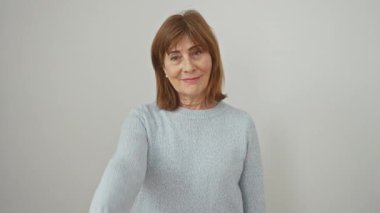 Dost canlısı, orta yaşlı İspanyol bir kadın, başarılı süveteri içinde duruyor, beyaz izole edilmiş arka planda hoş bir gülümseme ve el sıkışma sunuyor.