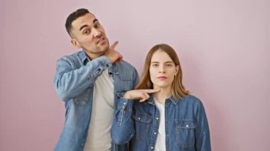 Kot gömlekli öfkeli çift tehditkar bir şekilde boğazlarını kesiyor, şiddeti işaret ediyor. Pembe izole arka planda agresif bir öfke gösterisi.