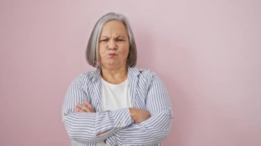 Orta yaşlı bir kadın inançsızlıktan çatık kaşlı, soyutlanmış pembe bir arka plan için gergin görünüyor. Gri saçlı, gömlek giyen şüpheci kişi rahatsız edici bir soruna üzülüp negatif titreşimler yayıyor..
