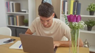 Ev ofisinde boynu ağrıyan genç bir İspanyol dizüstü bilgisayarla çalışıyor..