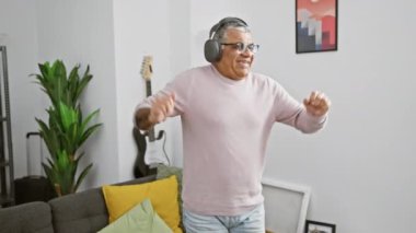 Evde kulaklıklarla dans eden neşeli son sınıf öğrencisi, modern dekorlarla çevrili.