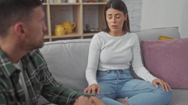 Endişeli bir adam ve üzgün bir kadın, rahat bir oturma odasındaki kanepede ciddi ciddi sohbet ediyorlar..