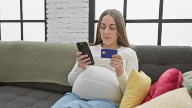 Kanepede akıllı telefon ve kredi kartı kullanan İspanyol bir kadının online alışveriş ya da bankacılık....