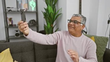 Gri saçlı olgun bir adam evdeki bir video görüşmesi sırasında başparmak kaldırıyor..