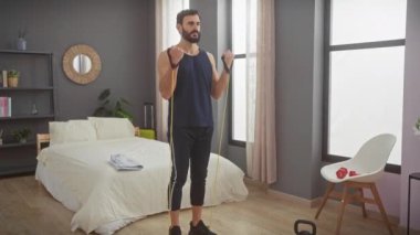 Orta yaşlı, sakallı bir adam modern yatak odasındaki direniş bantlarını kullanıyor..