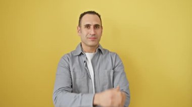 Gömlekli cesur, genç, İspanyol bir adam, kameraya aşkla doldurulmuş bir öpücük yolluyor. Sevimli bir yüz ifadesi, canlı sarı bir duvara karşı izole edilmiş duruyor..