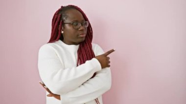 Pembe arka planda poz verirken örgülü ve gözlüklü kendinden emin Afrikalı kadın..