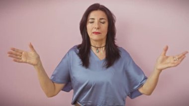 Orta yaşlı İspanyol kadın rahat ve gülümsüyor gözleri kapalı parmaklarıyla meditasyon hareketi yapıyor. Yoga konsepti izole edilmiş pembe arkaplan