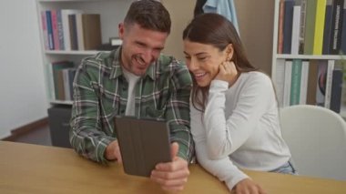 Gülümseyen bir çift, modern bir oturma odasında bir tabletle birlikte vakit geçirmekten zevk alır, sıcaklığı ve mutluluğu aktarırlar..