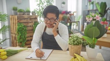Çiçekçide genç bir Asyalı telefonda konuşurken taze lalelerin yanına notlar yazıyor..