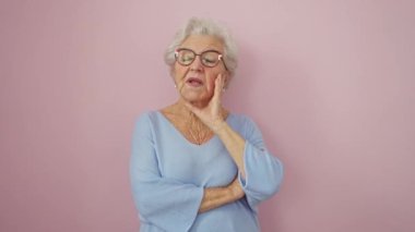 Sıkılmış, yorgun ve üzgün orta yaşlı kadın, kollarını kavuşturmuş depresyon sorunlarını düşünüyor, pembe arka planda tek başına duruyor.