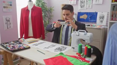Sakallı yakışıklı bir İspanyol, iyi donanımlı bir terzi dükkanında moda tasarımlarını inceliyor..