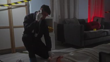 Genç bir İspanyol erkek dedektif telefonda konuşurken olay yerinde bir cesedi inceliyor..